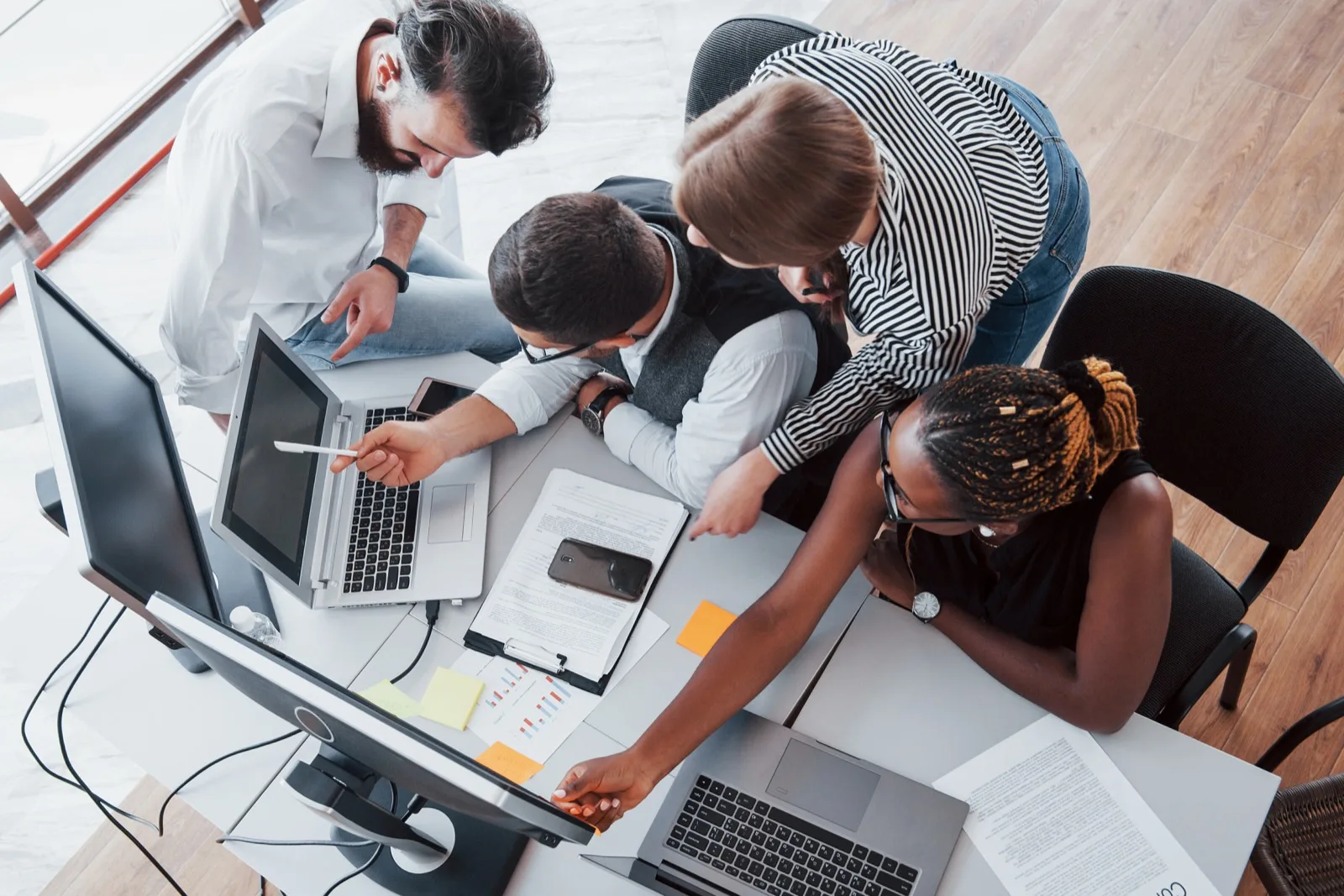 Diverse team collaborating over laptops and documents